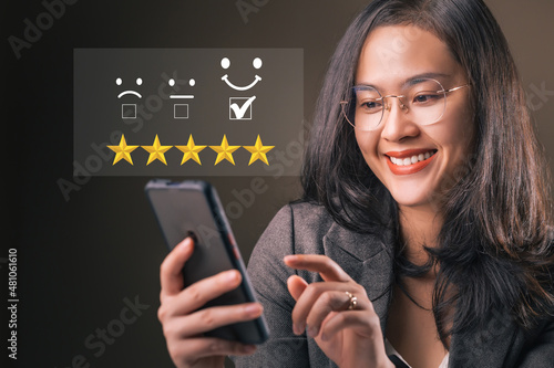 Smiley woman holding smartphone giving feedback consumer or review evaluation, satisfaction level. Business satisfaction support. Humans rate and giving stars.