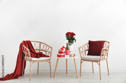 Gifts for Valentine's Day and red wine with rose flowers on table in room