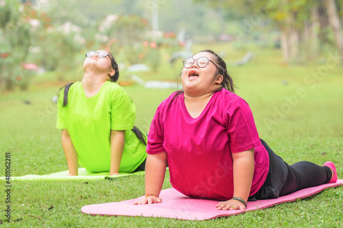 Obraz na plátne young woman with down syndrome or autism and friend doing yoga