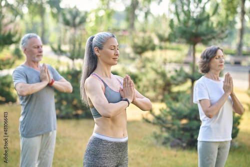 People in the park standing with hands in namaste and their eyes closed