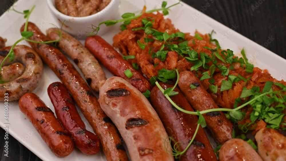 Tasty grilled different sausages with greens and sauce on the plate. Grilling food, bbq, barbecue, 4k Tasty grilled different sausages with greens and sauce on the plate. Grilling food, bbq, barbecue, 4k