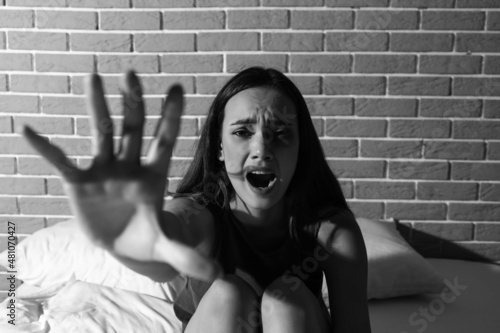 Scared young woman on bed. ...
