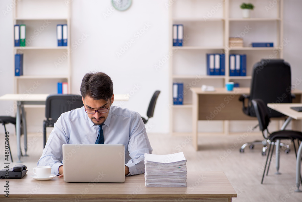 Young male employee unhappy with excessive work in the office Young male employee unhappy with excessive work in the office