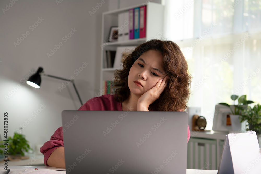 Feeling tired and stressed. Young Asian woman sitting looking deep in thought exhausted and tired during working at home office using laptop. Overworked tired Asian female student Feeling tired and stressed. Young Asian woman sitting looking deep in thought exhausted and tired during working at home office using laptop. Overworked tired Asian female student