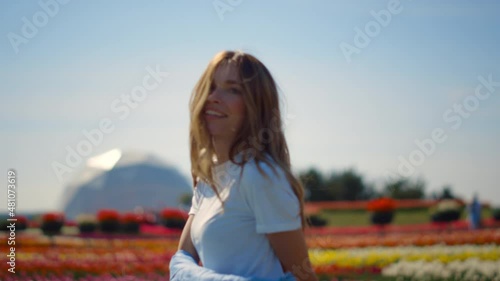 Beautiful girl dancing in flower garden. Young lady feeling joy in spring park. photo