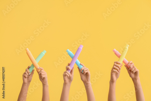 Hands with popular pop tubes on color background