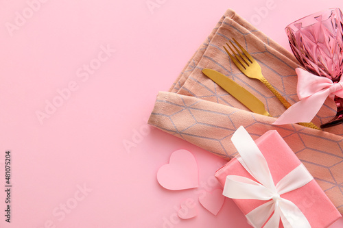 Beautiful cutlery, gift box and hearts on pink background