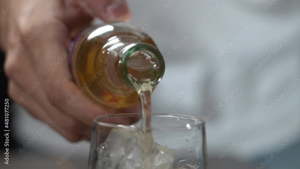 Making cocktail pouring ginger ale mixer from glass bottle into tall