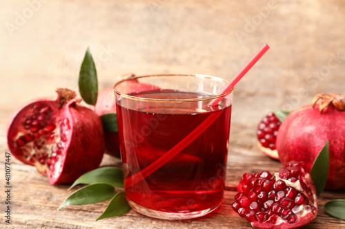 Glass of delicious pomegranate juice on wooden background