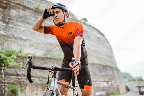 Fototapeta Naklejka Na Ścianę i Meble -  male cyclist feeling tired and wipe his sweat