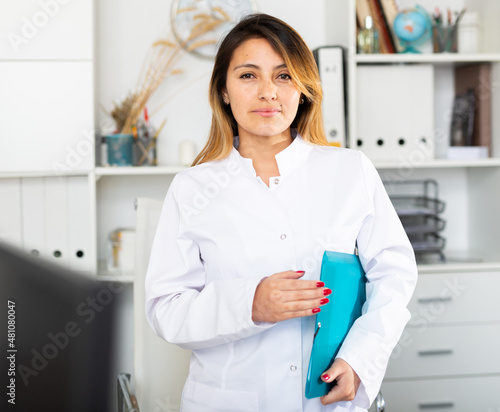 Portrait of latino female doctor posing in office and friendly smiling