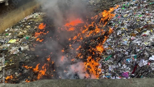 Fire burning trash heap, pouring water to extinguish - environment pollution concept
