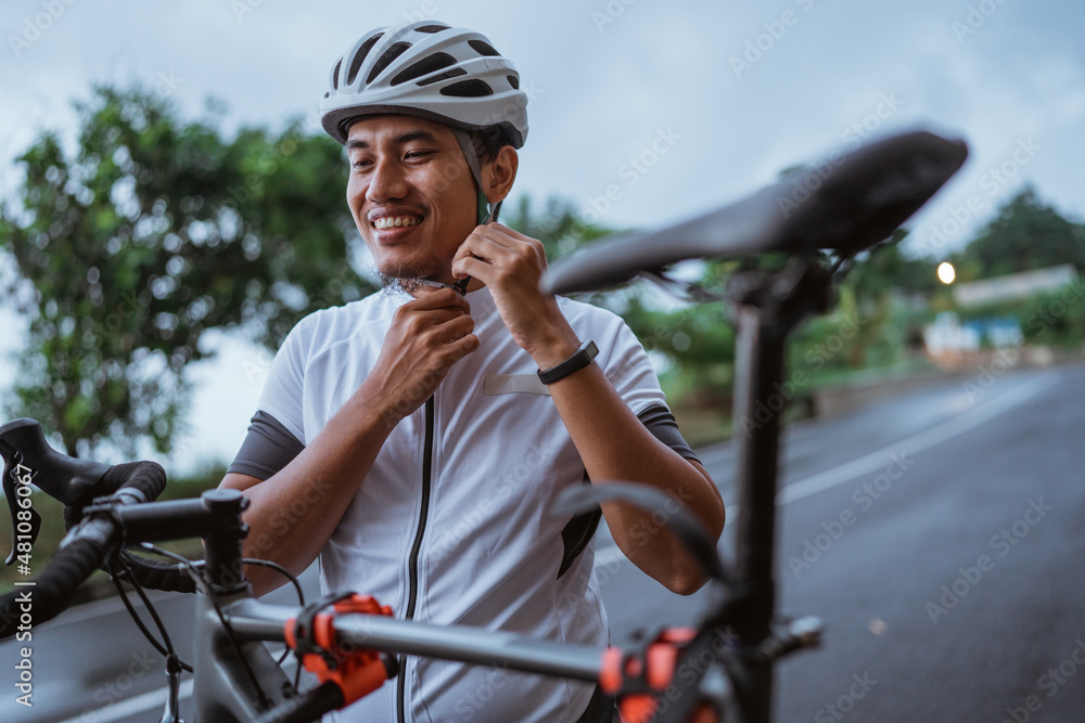 Fototapeta premium Young man cyclist wearing his sports helmet outdoor