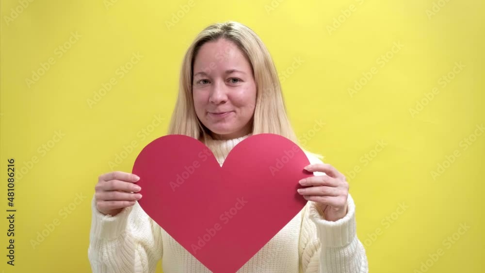 4k. Happy Young smiling woman with a hand-made paper heart in her hands expresses delight and joy , demonstrating love care on yellow background. Valentine's Day, Mothers day, Birthday 4k. Happy Young smiling woman with a hand-made paper heart in her hands expresses delight and joy , demonstrating love care on yellow background. Valentine's Day, Mothers day, Birthday