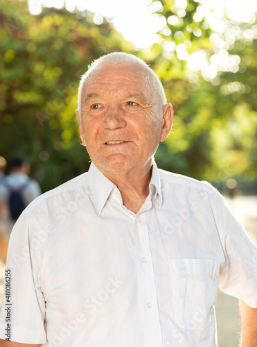 Portrait of smiling elderly man in park on sunny day