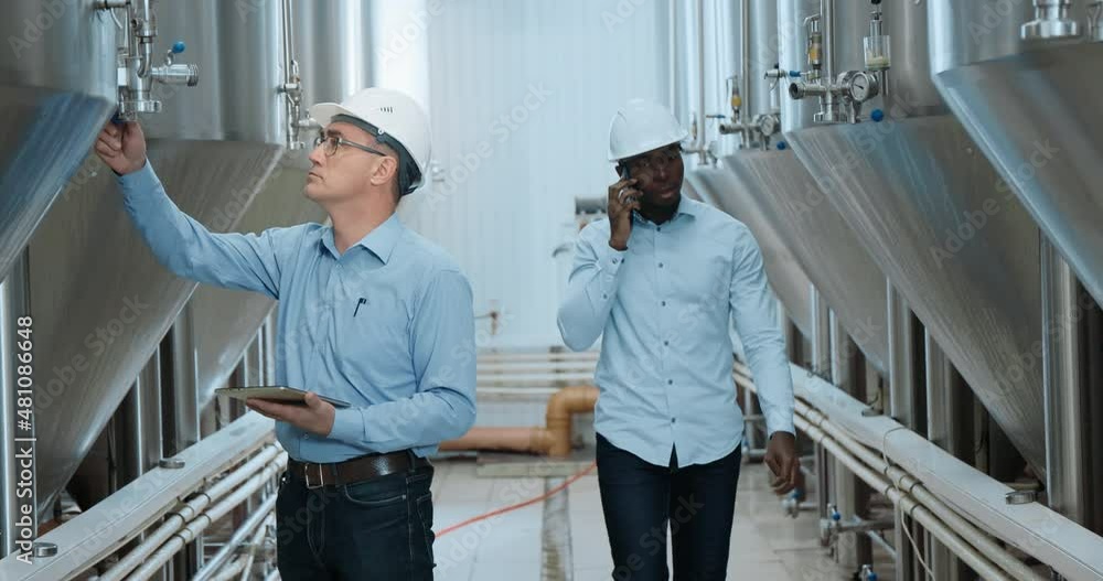 Two Industry Engineers Walk in Factory, Use Tablet and Discuss Work Two Industry Engineers Walk in Factory, Use Tablet and Discuss Work