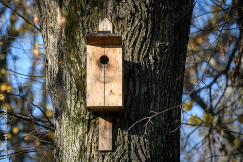 Selective focus photo. Wooden bird house on tree trunk.