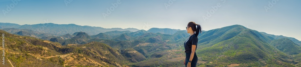 Young woman with a panoramic view of the Oaxacan mountains. Young woman contemplates the beautiful view of the mountains on a sunny morning. Vacation and travel concept. Young woman with a panoramic view of the Oaxacan mountains. Young woman contemplates the beautiful view of the mountains on a sunny morning. Vacation and travel concept.