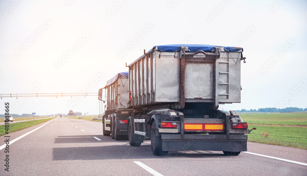 Transportation of grain in a dump truck with a trailer covered with an awning on the road. Agribusiness, copy space for text