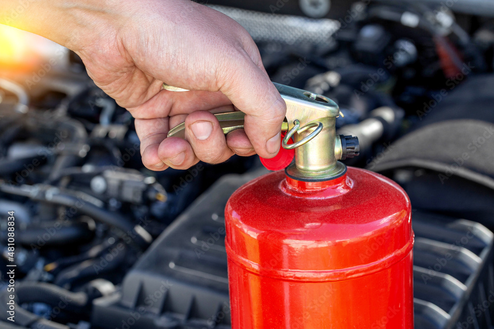 Car fire extinguisher on the background of the car engine