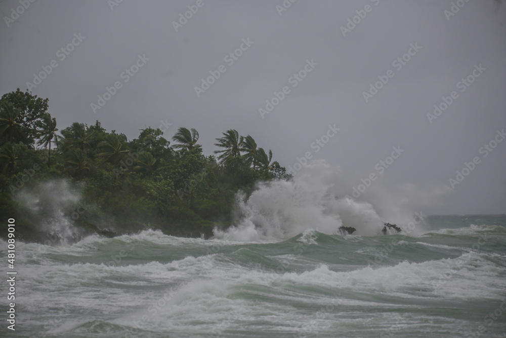 sea spray and surf on rocks in a storm with high waves on tropical cyclone