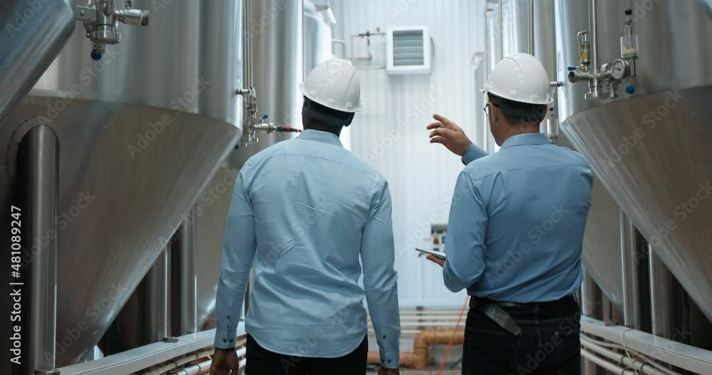 Two Industry Engineers Walk in Factory, Use Tablet and Discuss Work Two Industry Engineers Walk in Factory, Use Tablet and Discuss Work