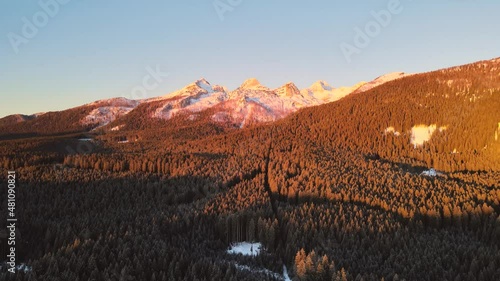 Nature captured with a drone with landscape and mountains covered in snow at golden hour at sunrise with beautiful forest and surrounding hills captured in Slovenia above forest Pokljuka in 4k photo