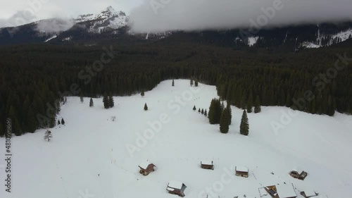 Nature captured with a drone with the landscape, mountains covered in snow at golden hour at sunrise with  forest and surrounding hills captured in Slovenia above forest Pokljuka  above a village photo