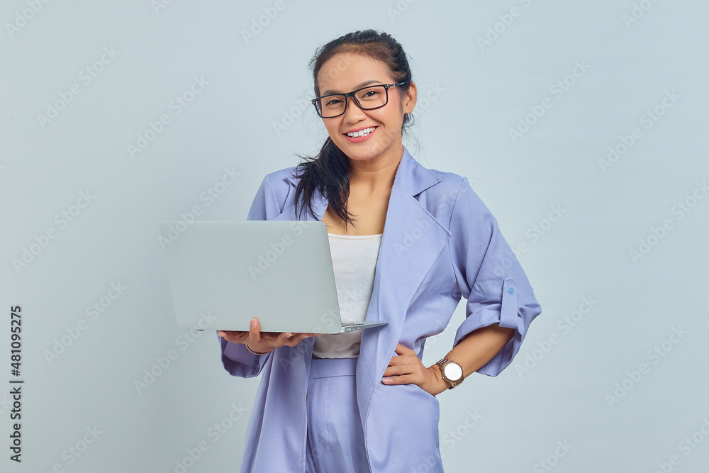 Portrait of cheerful young Asian woman using laptop and looking at camera isolated on white background Portrait of cheerful young Asian woman using laptop and looking at camera isolated on white background