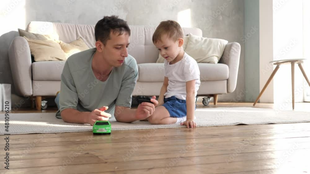 Caring young father plays with his preschool son, drives a radio-controlled toy car, loves to spend time together. Young family having fun playing Caring young father plays with his preschool son, drives a radio-controlled toy car, loves to spend time together. Young family having fun playing