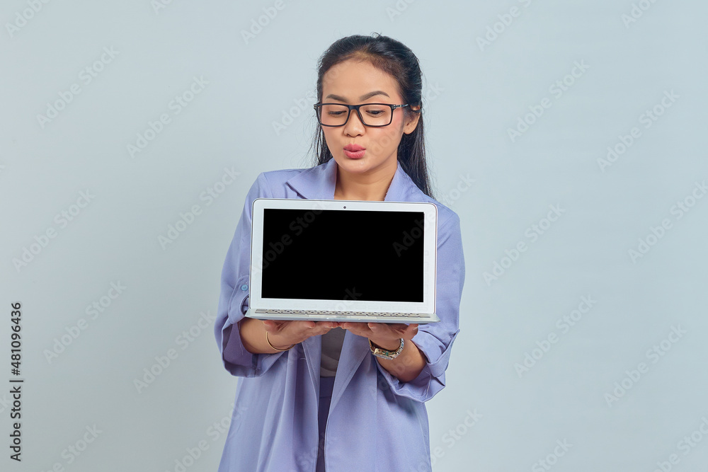 Portrait of cheerful young Asian business woman showing blank laptop screen to present products isolated on white background Portrait of cheerful young Asian business woman showing blank laptop screen to present products isolated on white background