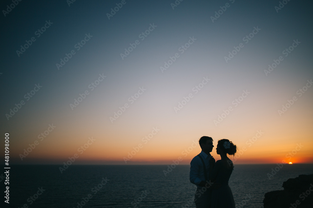 Beautiful sunset at sea, a man and a woman hold hands, look at each other, a love