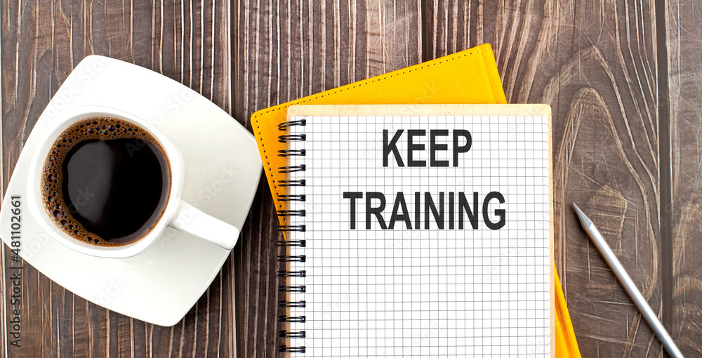 KEEP TRAINING text on the notebook with coffee on wooden background KEEP TRAINING text on the notebook with coffee on wooden background