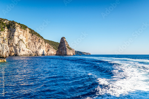 Layered rocky cliffs with plants near shore of Corfu island