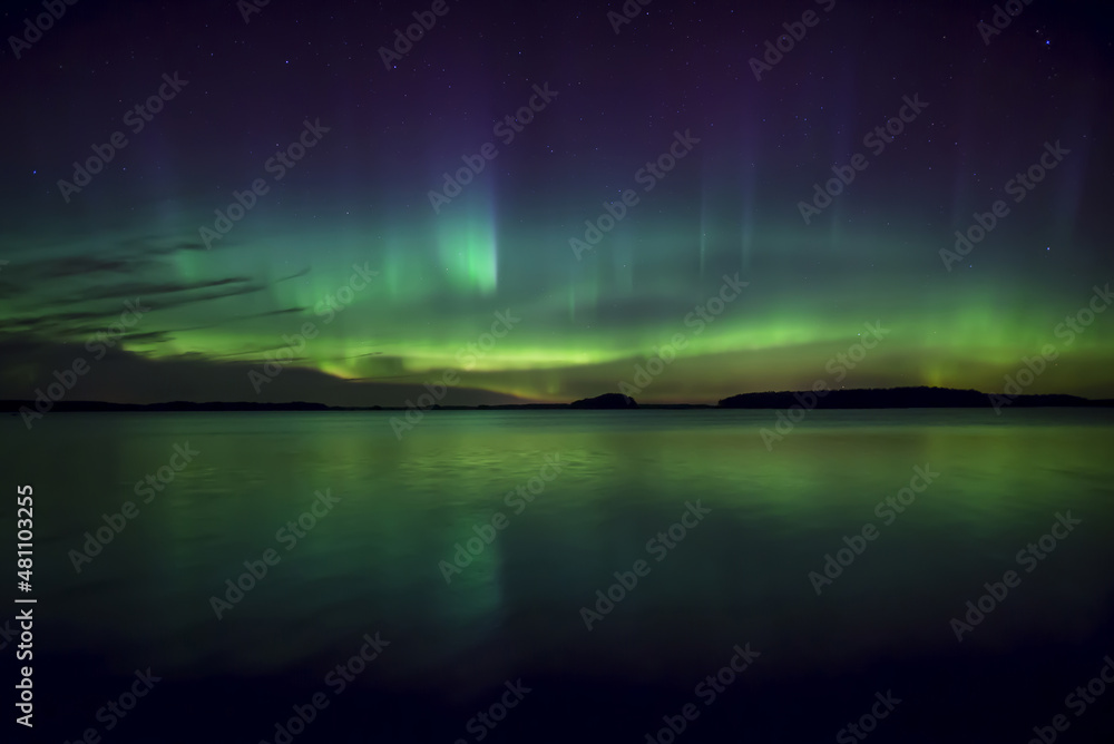 Northern lights dancing over calm lake in north of Sweden.