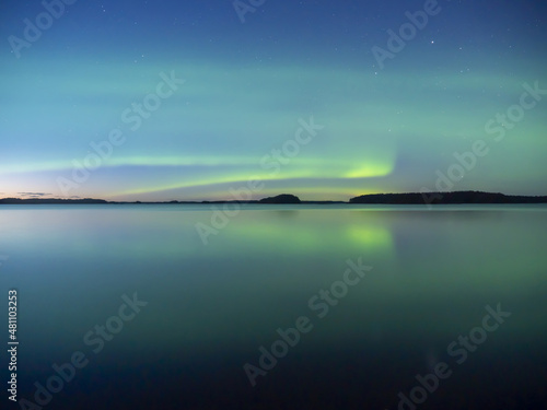 Northern lights dancing over calm lake in north of Sweden.