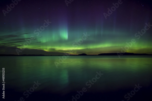 Northern lights dancing over calm lake in north of Sweden.
