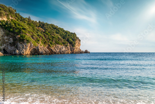 Calm beach of Mediterranean sea near high hill with forest