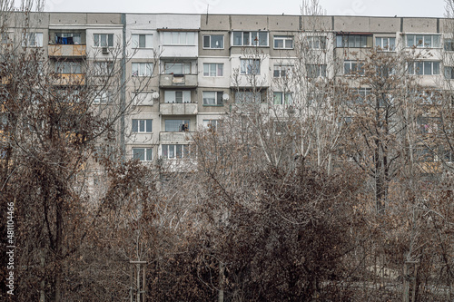 Billede på lærred A gray residential building from the socialist era, made of prefabricated concrete panels in Sofia the capital of Bulgaria, autumn trees with fallen leaves in the foreground, depressing cityscape