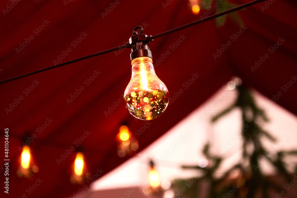 Christmas interior decoration, light bulbs and lanterns. The interior is in red and gold tones, the concept of Christmas decorations.