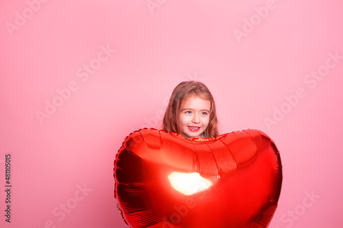 Beautiful child girl with red heart balloon on pink background celebrating Valentine day © Юля Шевцова
