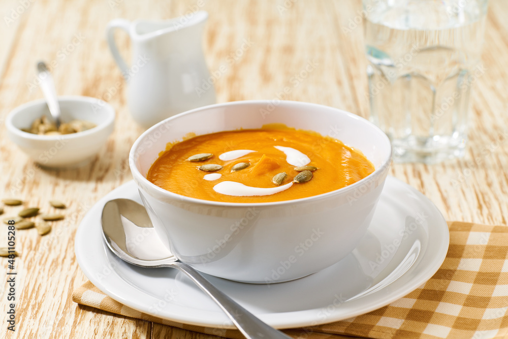 Bowl of homemade soup with organic pumpkin with cream sauce, on a white wooden table. Bowl of homemade soup with organic pumpkin with cream sauce, on a white wooden table.