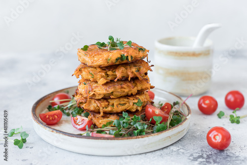 Vegan herb sweet potato fritters served with fresh salad on ceramic plate. Plant based diet concept. copy space