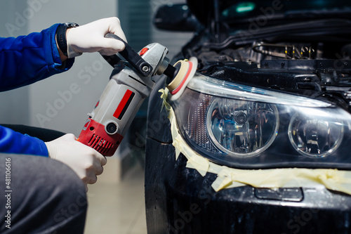 Car headlights cleaning with power buffer machine at car service photo