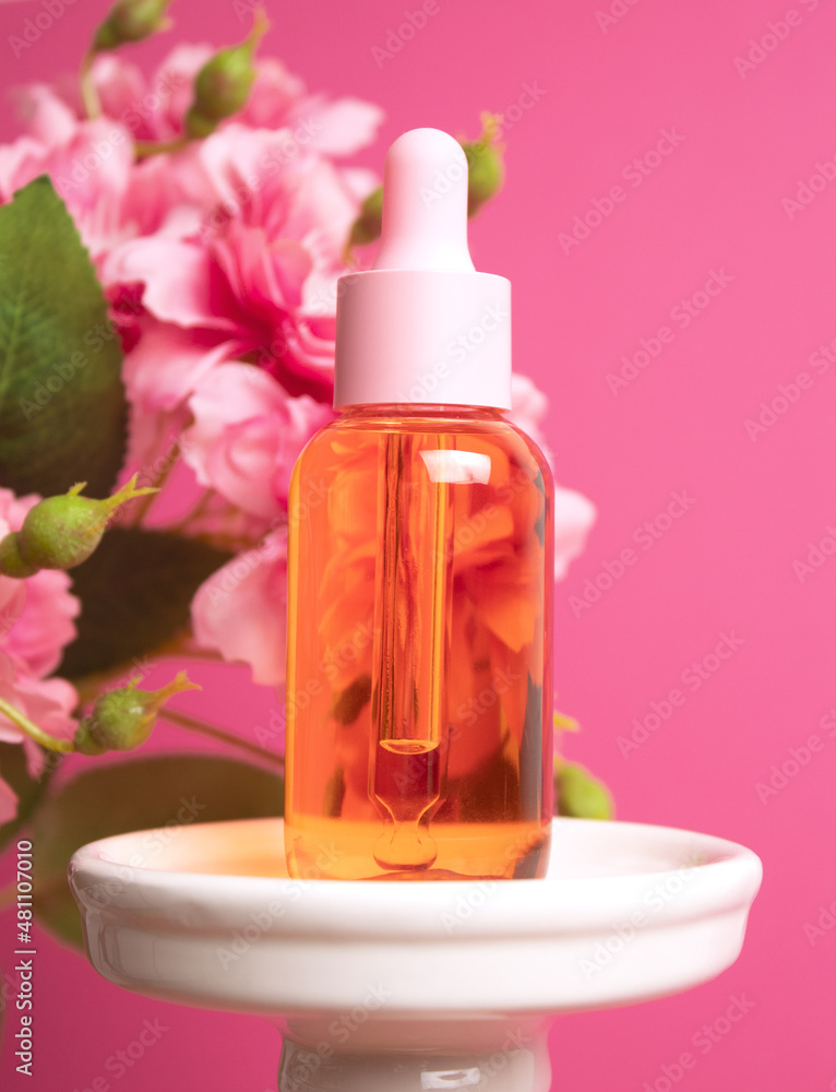 Glass dropper bottle on podium with flowers on pink background. Cosmetic container mock-up. Background for branding and packaging presentation. Natural skincare beauty product concept Glass dropper bottle on podium with flowers on pink background. Cosmetic container mock-up. Background for branding and packaging presentation. Natural skincare beauty product concept