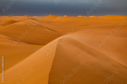Strong wind at sunset over the sand dunes in the desert. Sandstorm in the Desert