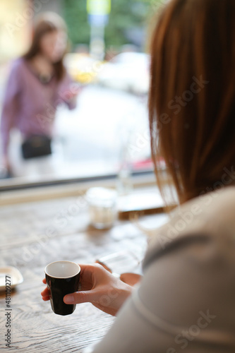 Lifestyle photo of woman in restaurant terrace holding a cup of espresso coffee on a summer day. Relaxing after shopping. Copy space for message. 