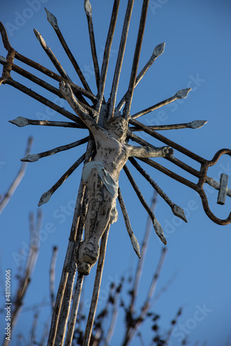 Old metal cross with a crucifix on a cloudless sky background. Vertical image