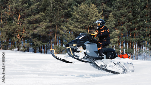 In deep powder snowdrift snowmobile rider driving fast.