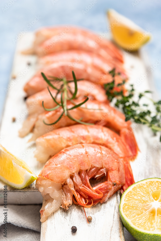 Raw Argentine shrimps on white wooden cutting board with lime, herbs and pepper. Seafood. Raw Argentine shrimps on white wooden cutting board with lime, herbs and pepper. Seafood.